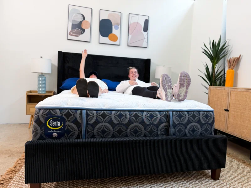 Two people test motion isolation on the Serta Perfect Sleeper Cascade Range Medium mattress