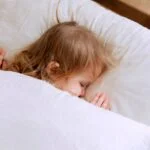 photo of child laying on bed 3933069