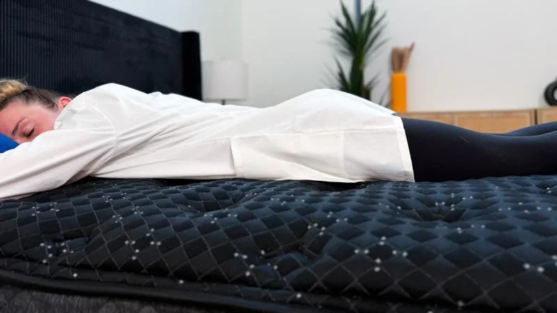 Product expert lying on stomach on Beautyrest-Black.