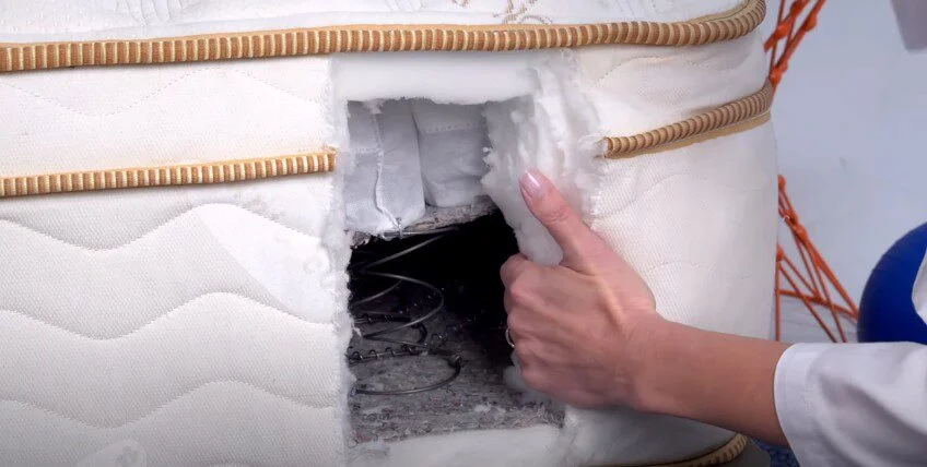 Saatva Mattress is cut open on the side to reveal layers of foam and coils.