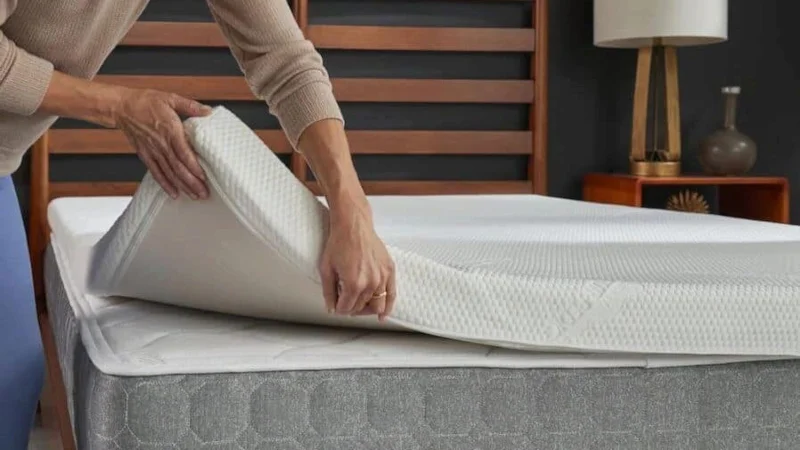 A person lifts the corner of a mattress topper