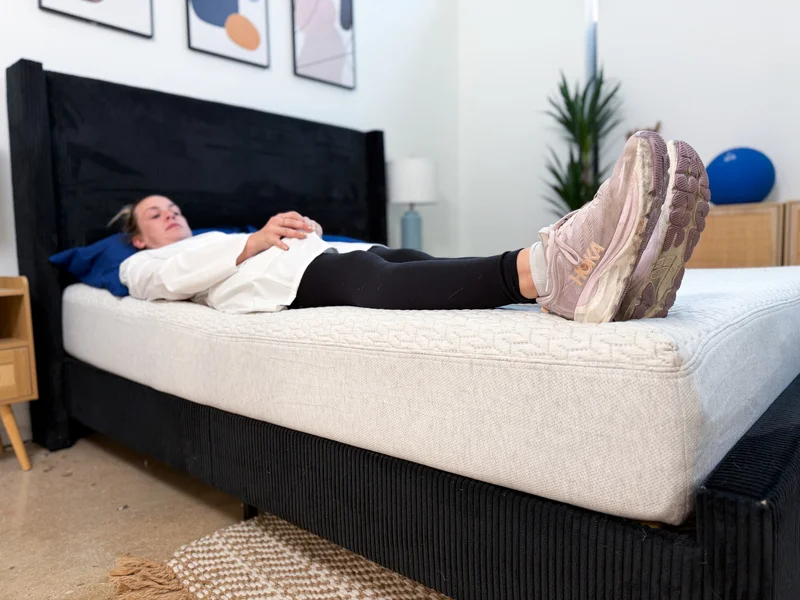 A tester resting on her back on the edge of the Tuft and Needle Original mattress